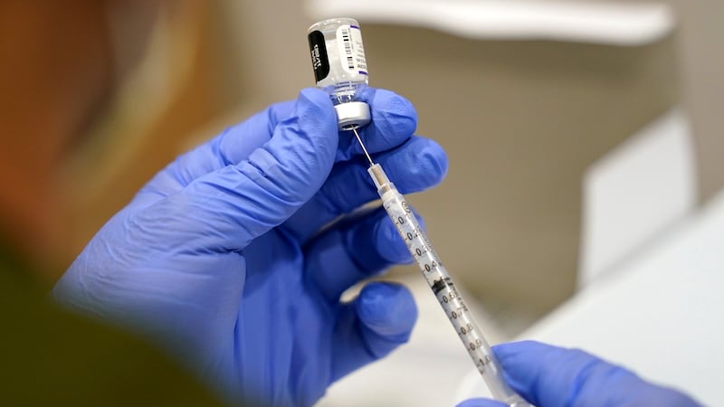 A health care professional fills a syringe with a vaccine.