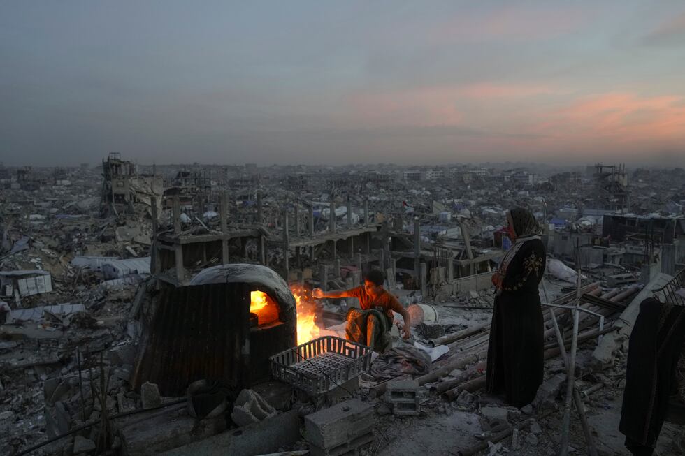 Palestinians Ali Marouf and his mother Aisha cook on fire on the roof of their destroyed house...